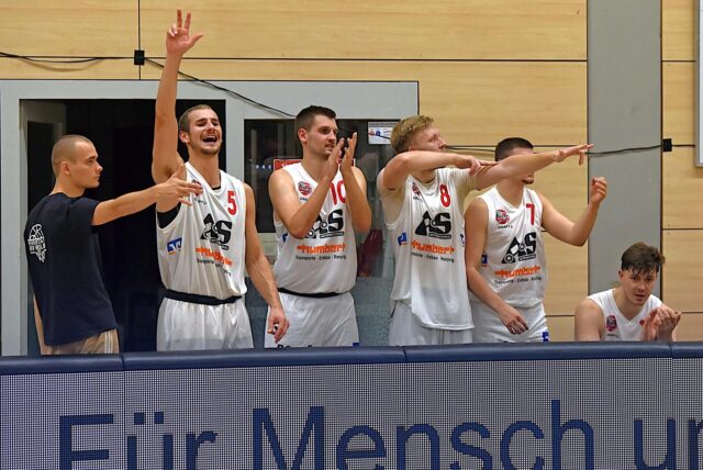 Basketball-Spieler des BSV Wulfen feiern auf der Bank einen Korberfolg.