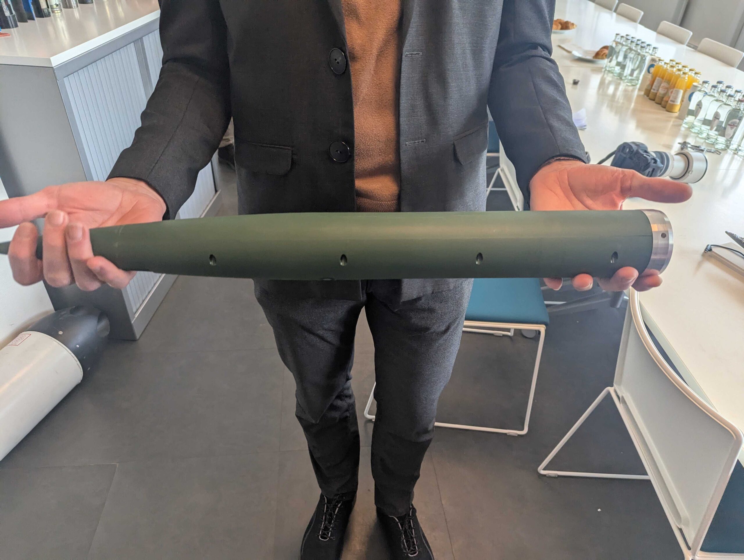 Ein Thales-Mitarbeiter hält ein Modell hoch, welches die relative Größe des FZ123-Sprengkopfs zeigt.