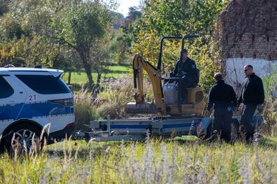 Polizisten untersuchen mit einem Bagger ein Grundstück in Tauche (Landkreis Oder-Spree). 