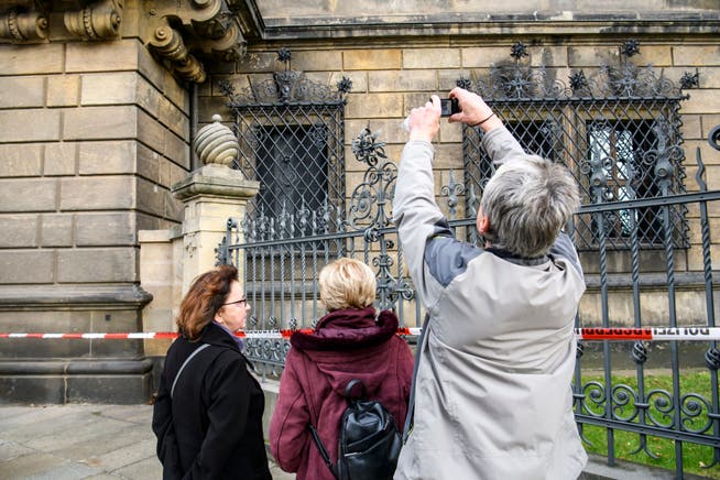 Passanten fotografieren das Fenster des Residenzschlosses, durch das die Einbrecher in das Museum in Dresden eingedrungen sind.
