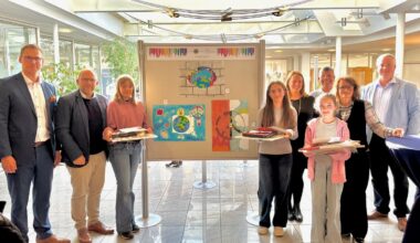 Ausstellung in der Bank: Hauke Klüssendorf (VR Bank), Bürgermeister Roger Nießen, Emily Pierednik (Platz 2), Mia Dobrijevic (Platz 1), Beate Roderburg Lions Club, Christof Klein VR Bank, Emma Rosenbaum (Platz 3), Svenja Harren-Poqué (Lions Club) und Frank Lüder (VR Bank) vor den drei Siegerbildern.