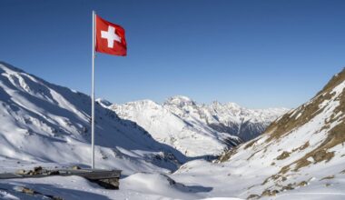 Das Bild zeigt eine Schweizer Flagge in einer schneebedeckten Berglandschaft.