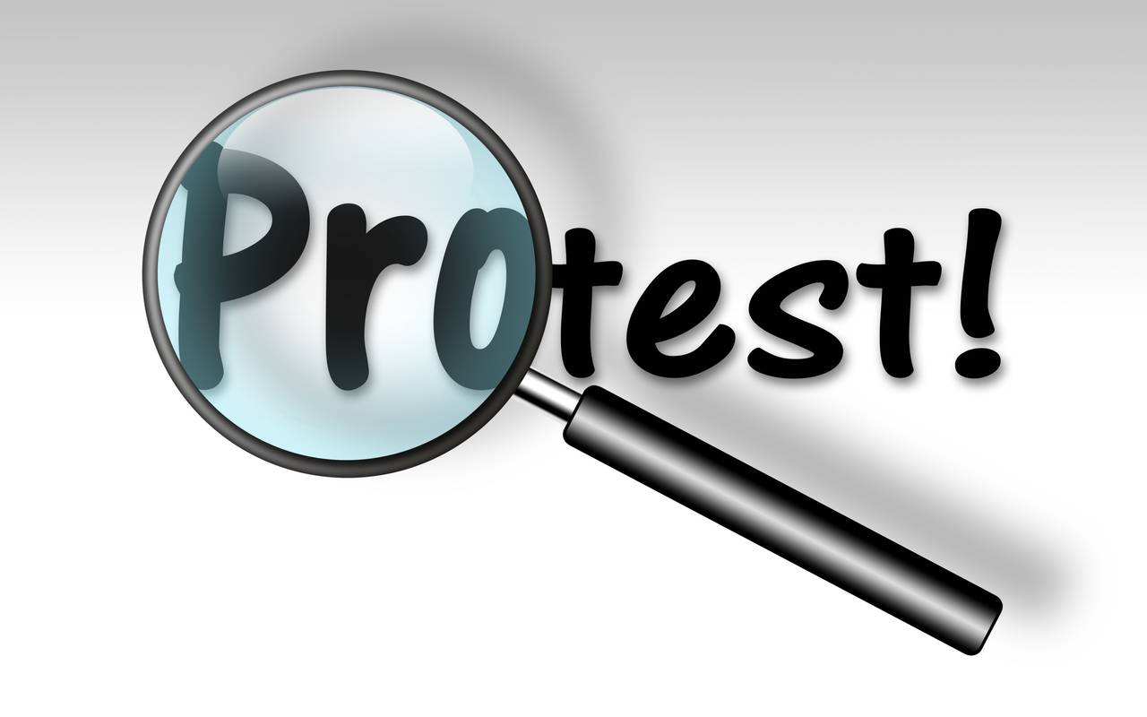 Eine Lupe vergrößert das Wort "Protest". 