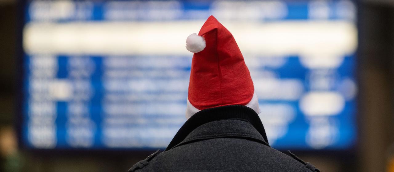 Ein Mann mit Weihnachtsmannmütze in einem Banhof