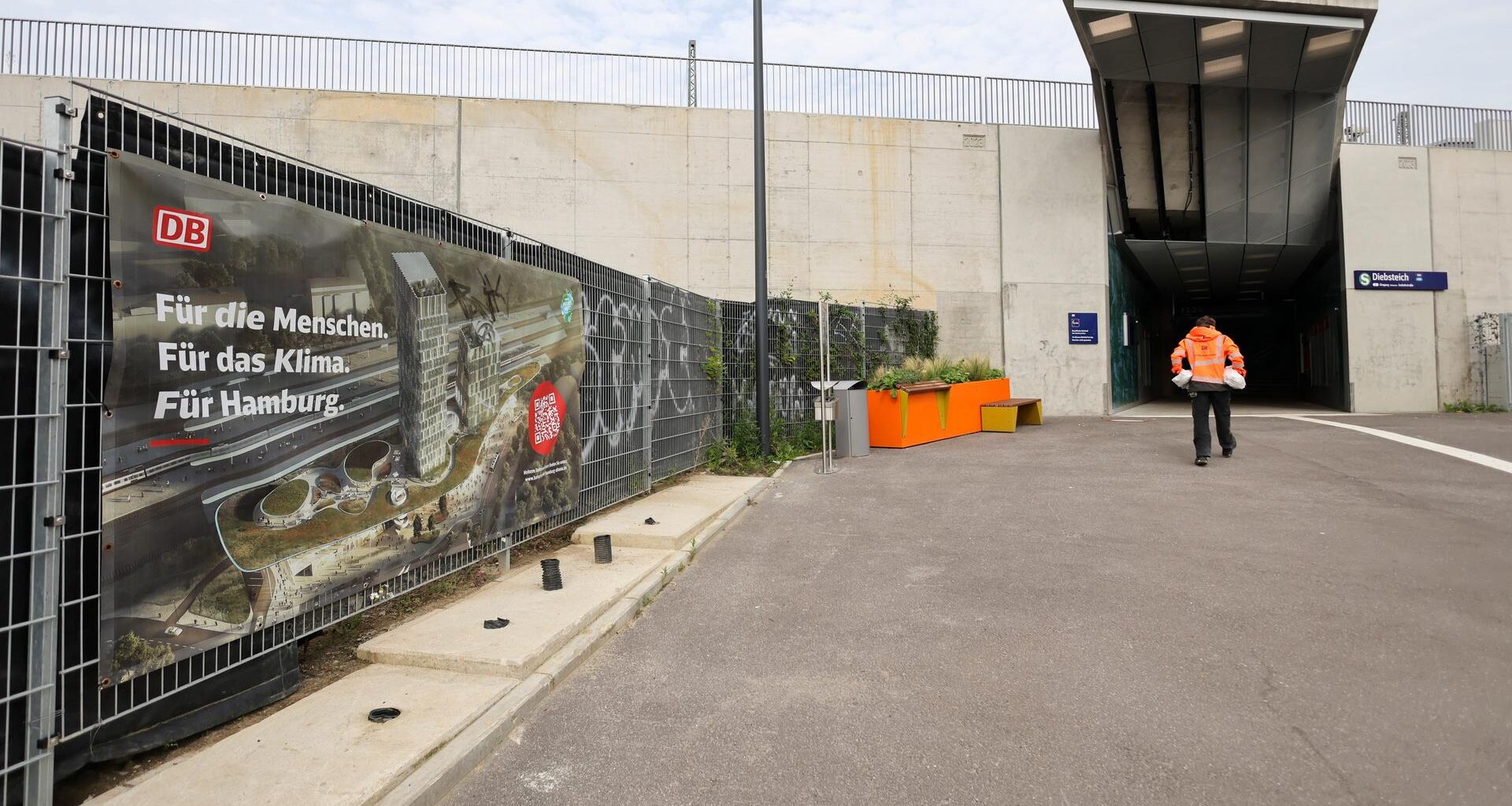 Hamburg: Ein Werbeplakat der Deutschen Bahn mit der Animation eines neuen Bahnhofs ist an einem Zaun neben dem Zugang zur umgebauten S-Bahnstation Diebsteich zu sehen.