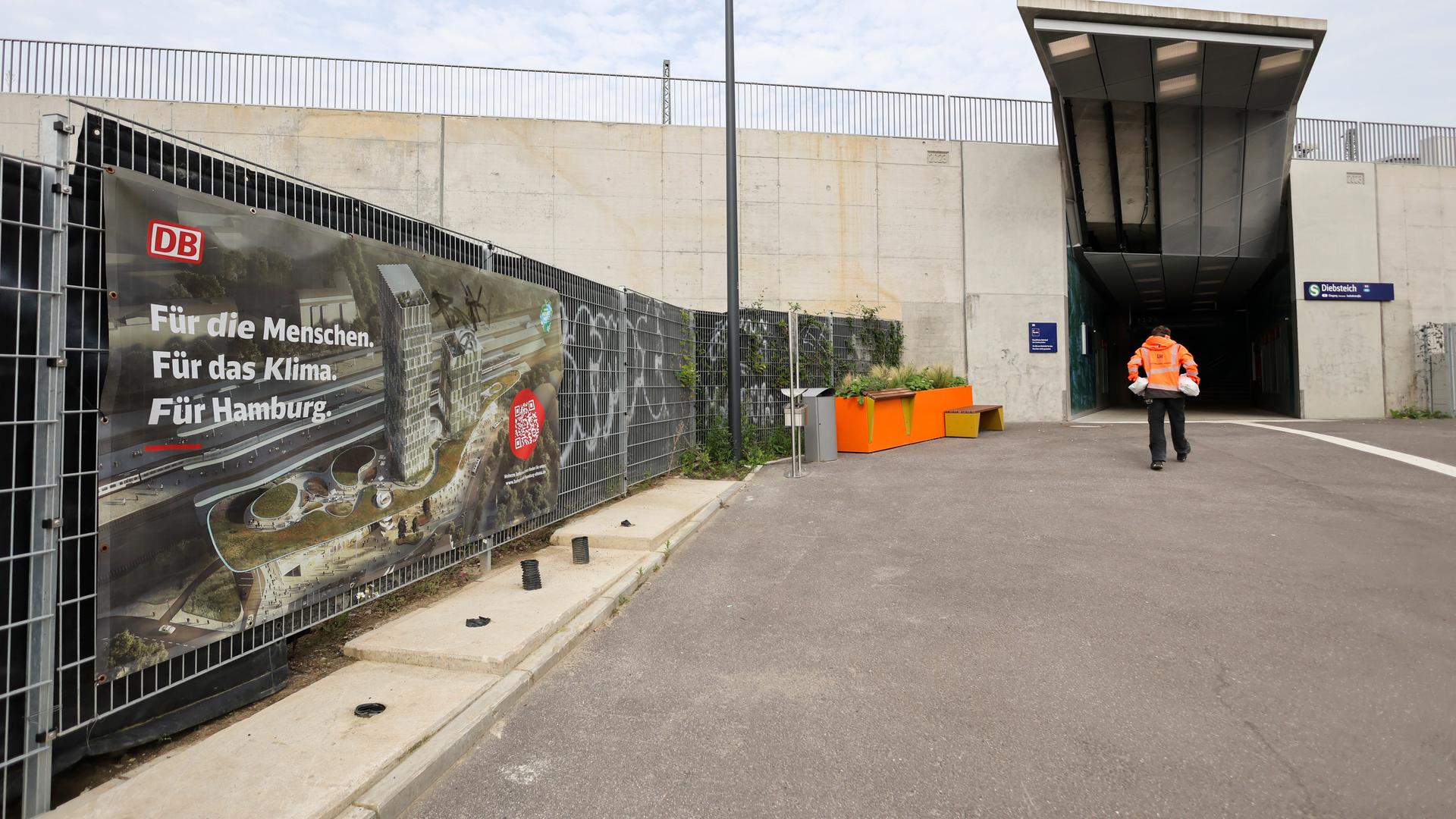 Hamburg: Ein Werbeplakat der Deutschen Bahn mit der Animation eines neuen Bahnhofs ist an einem Zaun neben dem Zugang zur umgebauten S-Bahnstation Diebsteich zu sehen.