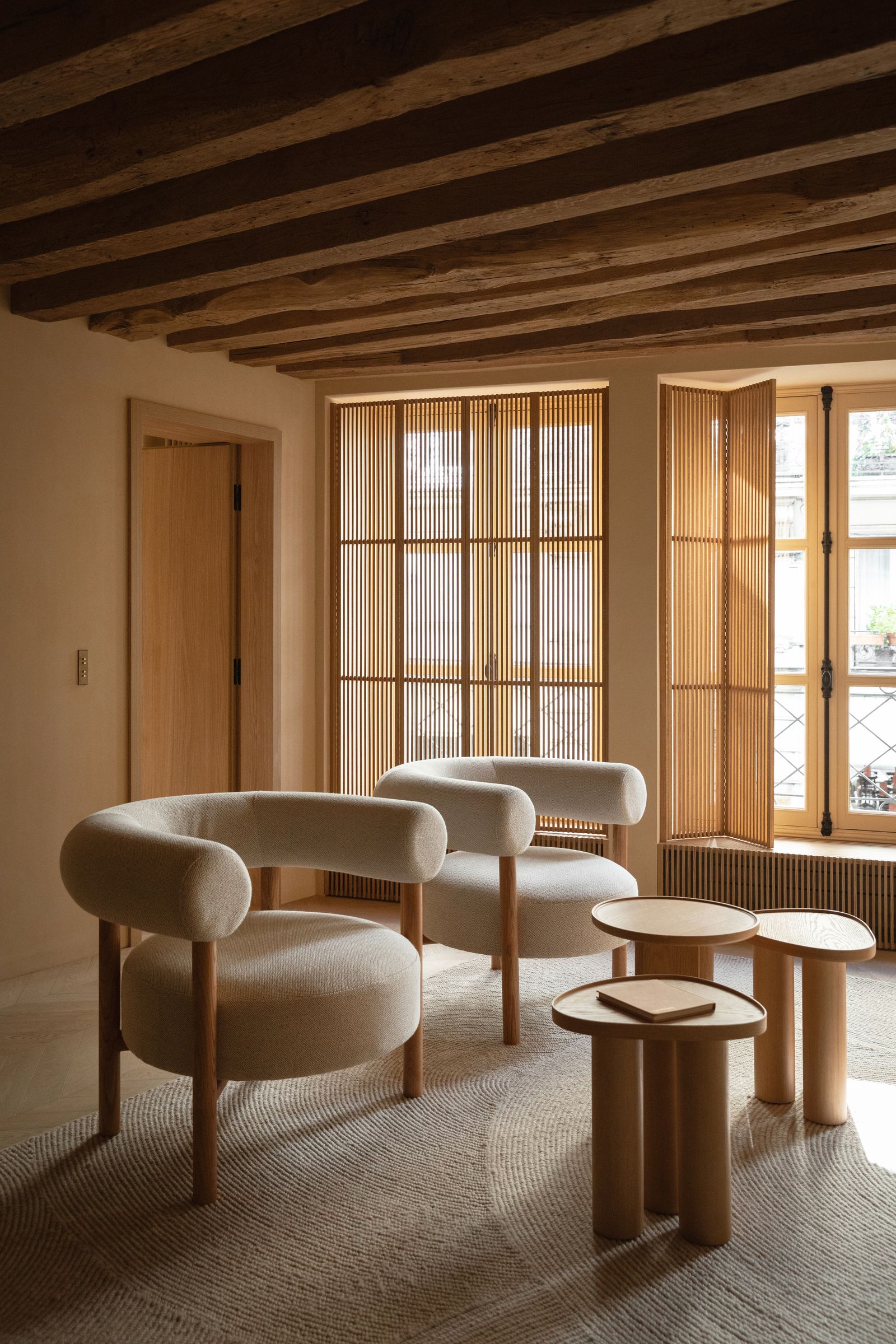 Wohnzimmer niedrige Decke cremefarbene Sessel hölzerne LamellenFensterläden