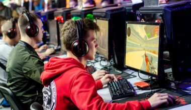 Mehrere junge Leute mit Headsets sitzen an Computern und spielen CS2, ein Ego-Shooter-Videospiel, bei einem esports-Event oder Gaming-Turnier.
