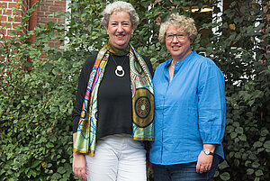 Lisa Frings und Sandra Middendorf stehen nebeneinander vor einer Hecke.