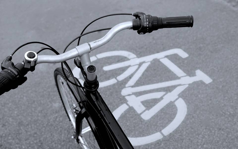 Der Lenker eines Fahrrades. Im Hintergrund ist ein Fahrrad-Symbol auf dem Boden zu sehen.