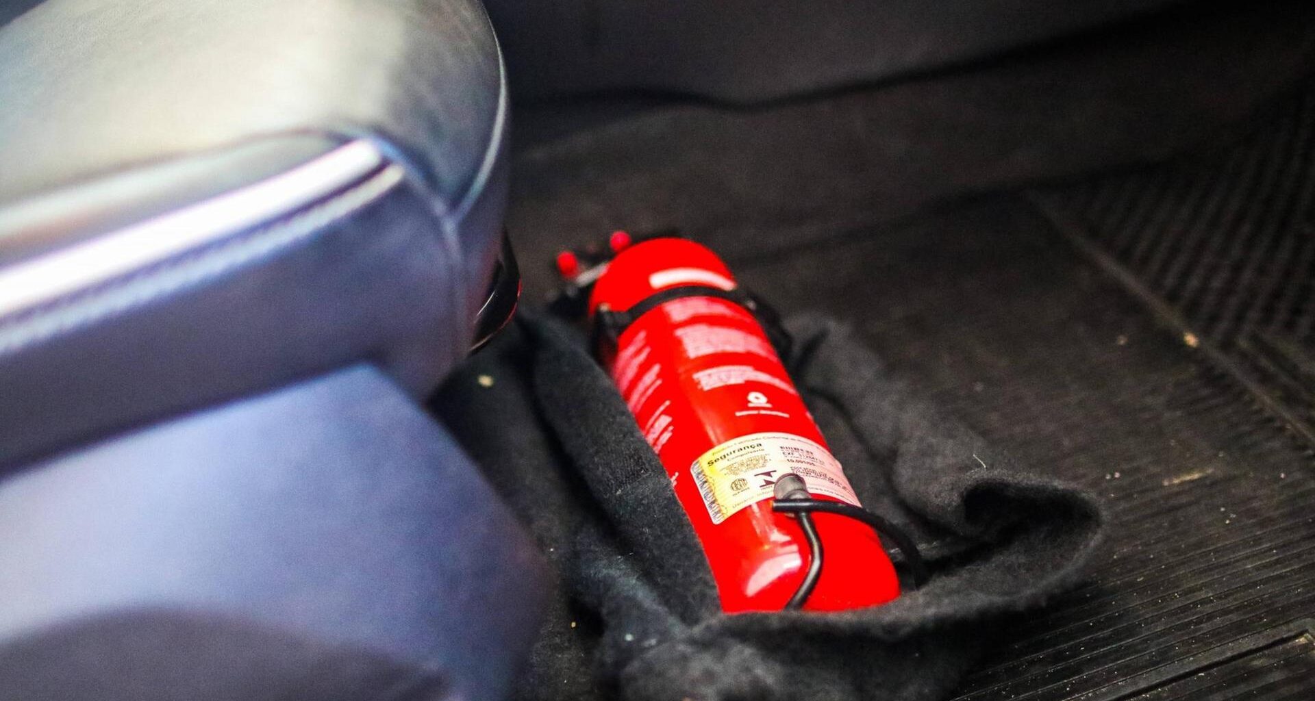 Ein Feuerlöscher liegt fest verschraubt unter dem Fahrersitz in einem Auto.