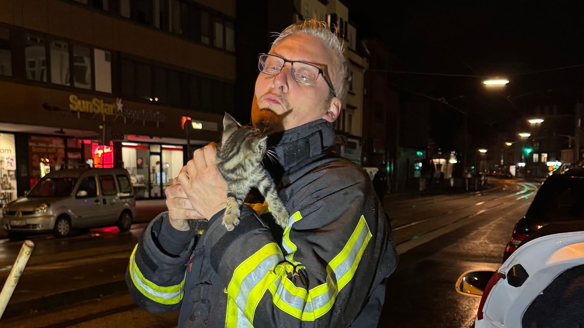 Feuerwehrmann hält das gerettete Kätzchen im Arm: Das Tier hatte sich während einer Autofahrt von Hannover nach Bochum im Radkasten versteckt. Feuerwehrmann hält das gerettete Kätzchen im Arm: Das Tier hatte sich während einer Autofahrt von Hannover nach Bochum im Radkasten versteckt.