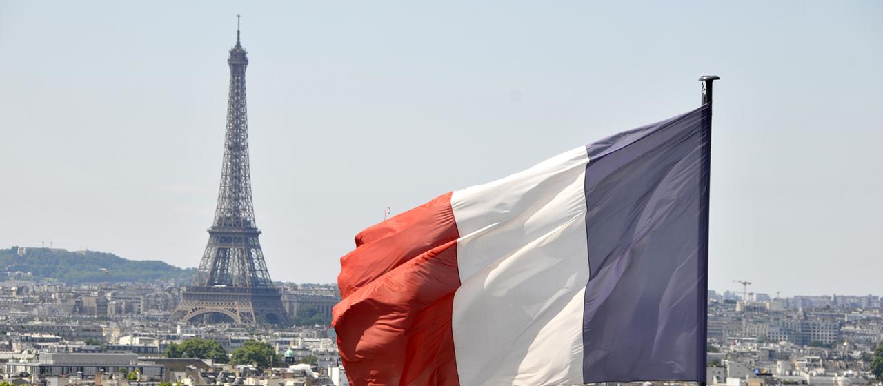 Die Flagge Frankreichs weht vor dem Eiffelturm in Paris.