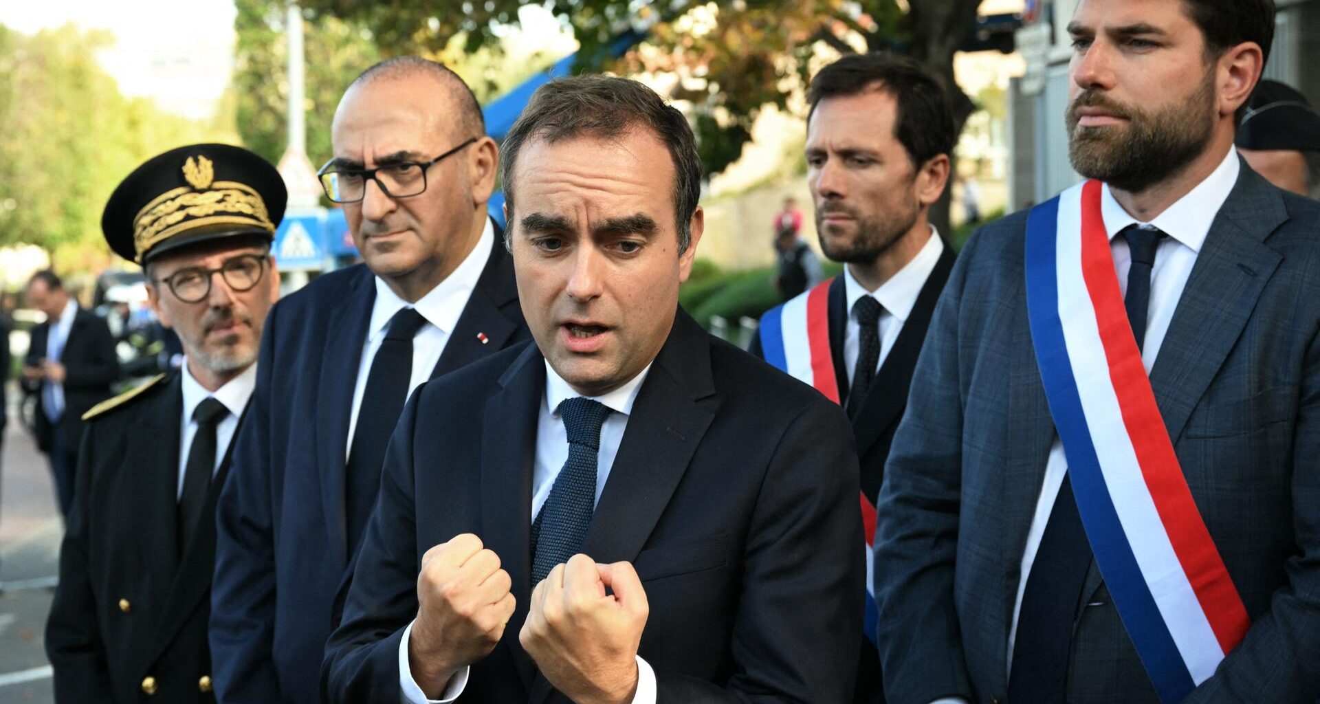 Der französische Premierminister Sébastien Lecornu ballt die Fäuste. An seiner Seite stehen mehrere Abgeordneten nach einem Besuch einer Polizeistation bei Paris.