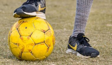 Ein Fußballer hat einen Fuß auf einen gelben Ball stellt.