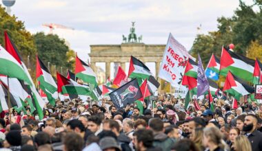 Demonstranten schwenken palästinensische Fahnen und halten Plakate hoch. Im Hintergrund ist das Brandenburger Tor zu sehen
