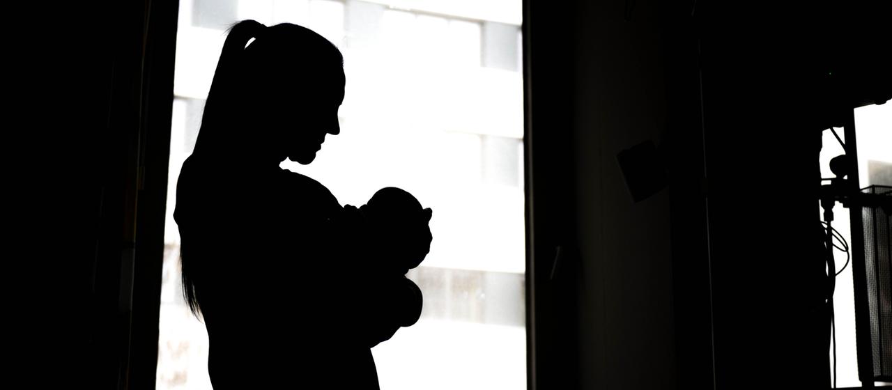 Eine Frau steht mit einem Neugeborenen am Fenster einer Klinik. | dpa Eine Frau steht mit einem Neugeborenen am Fenster einer Klinik.