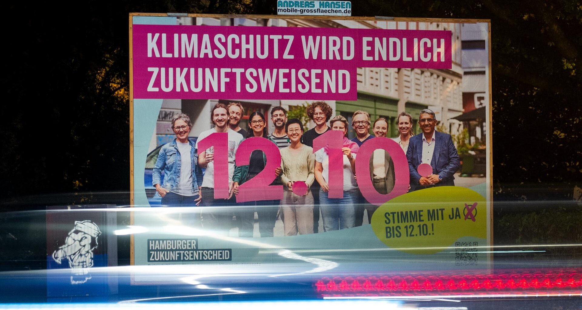 Ein Plakat für den Hamburger Zukunftsentscheid mit der Aufschrift "Klimaschutz wird endlich zukunftsweisend" steht an einer Straße.