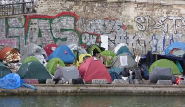 Blick vom anderen Seine-Ufer auf zahlreiche bunte Zelte an einer Ufermauer am Kai.