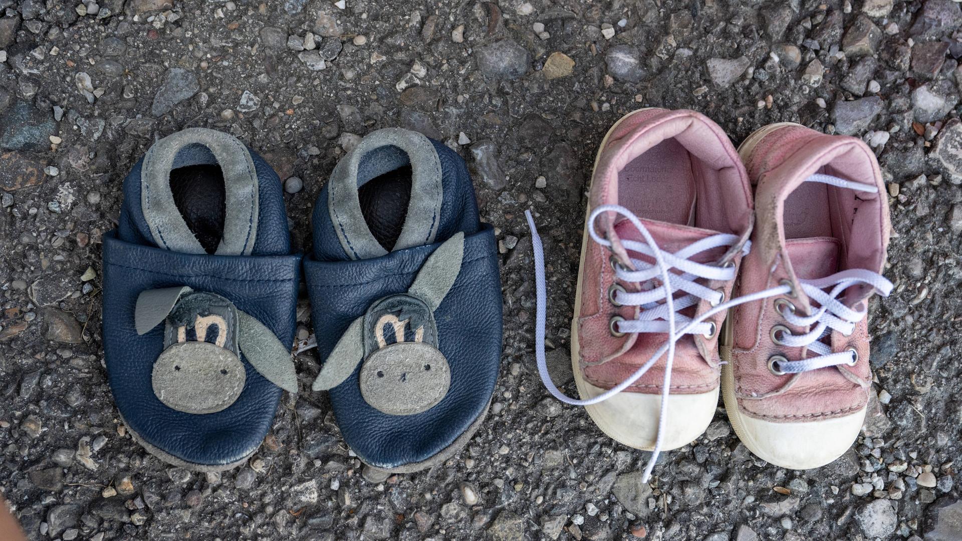 Zwei Paar Kinderschuhe aus einer Spendenkiste für Bedürftige stehen auf dem Asphalt Zwei Paar Kinderschuhe aus einer Spendenkiste für Bedürftige stehen auf dem Asphalt