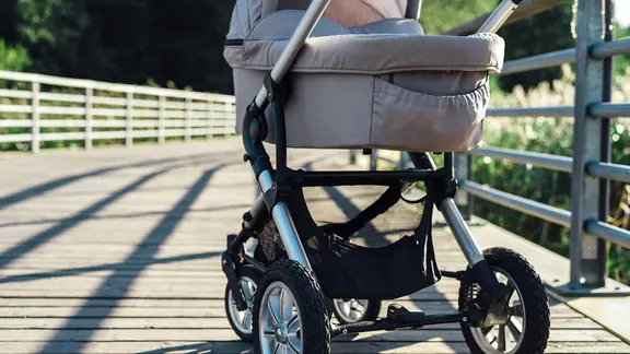 Ein Kinderwagen wird über eine Brücke geschoben.