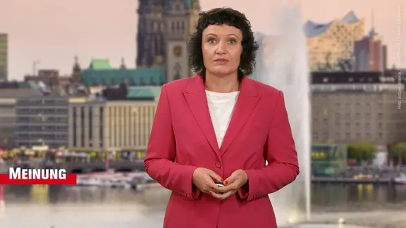 Eine Frau steht vor der Skyline von Hamburg.