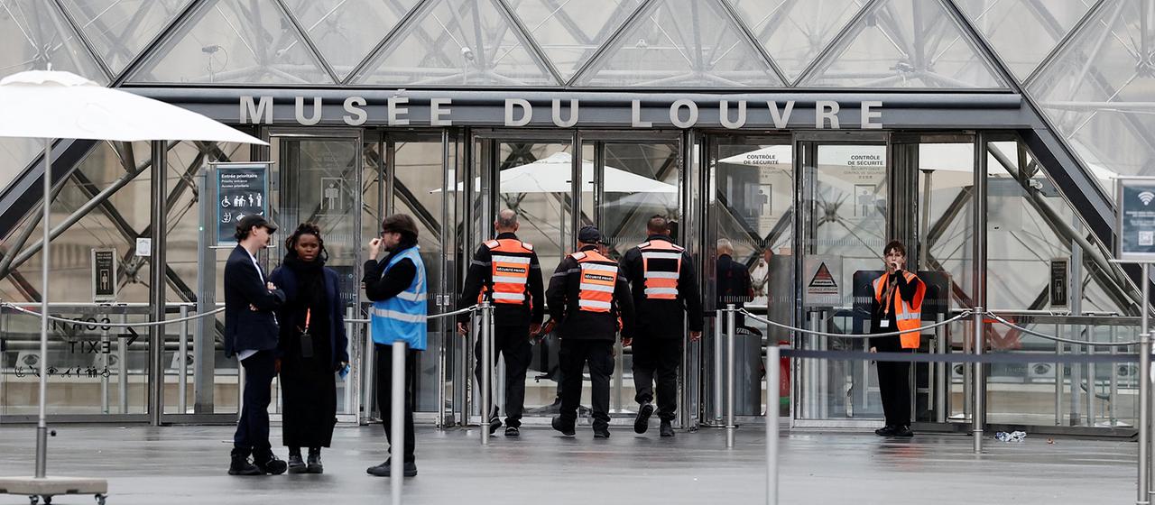 Mehrere Sicherheitskräfte in orangefarbenen Westen stehen vor dem Eingang des Louvre in Paris. | REUTERS Mehrere Sicherheitskräfte in orangefarbenen Westen stehen vor dem Eingang des Louvre in Paris.