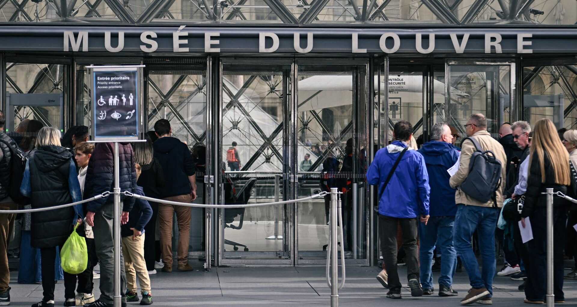 Menschen warten am Eingang des Museums Louvre in Paris.