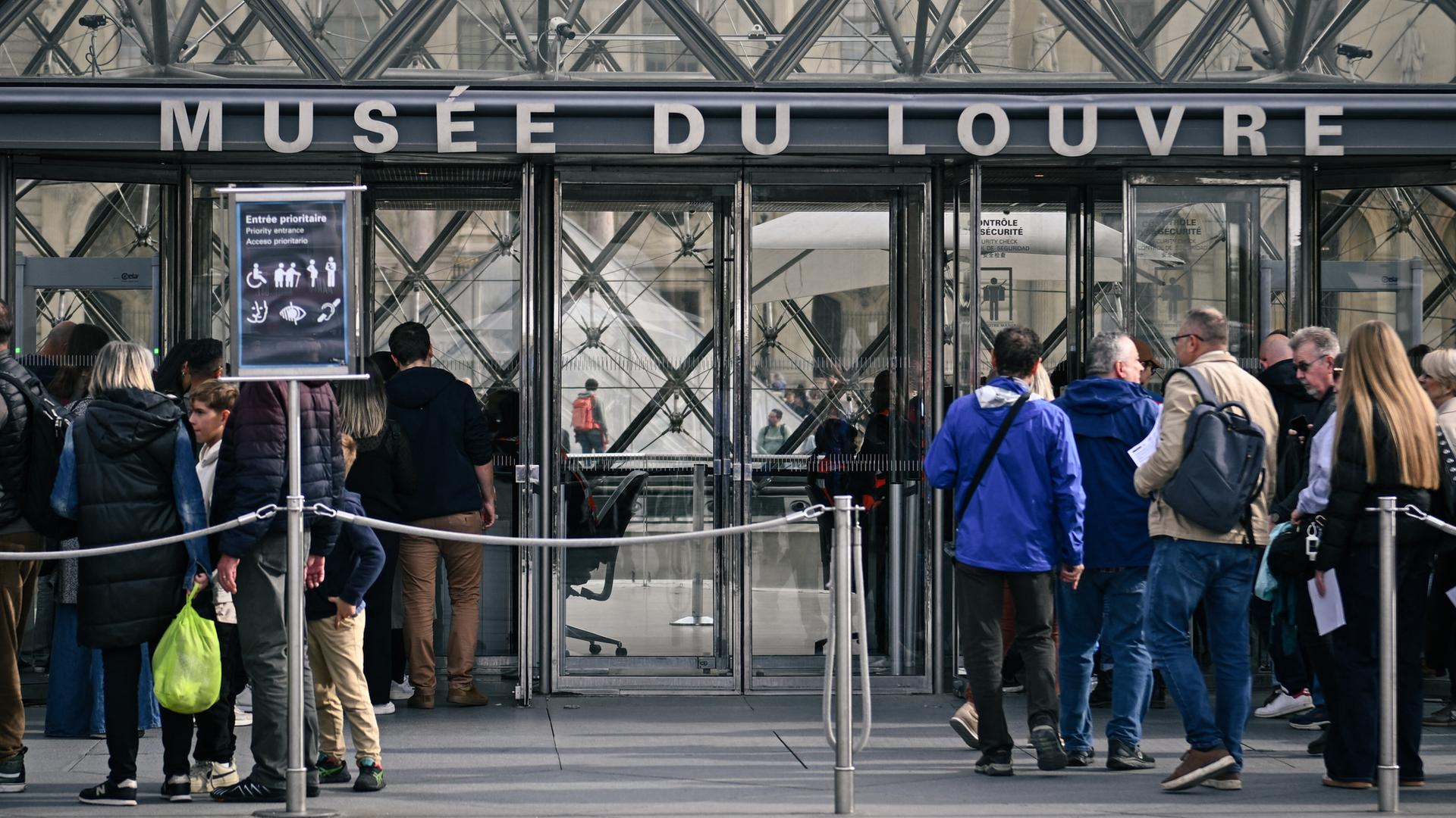 Menschen warten am Eingang des Museums Louvre in Paris.