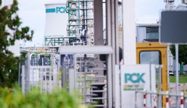 Das Bild zeigt das Werksgelände der Raffinerie PCK in Schwedt. Das Logo PCK ist im Vordergrund am Eingang zu sehen und im Hintergrund an einem Tank.