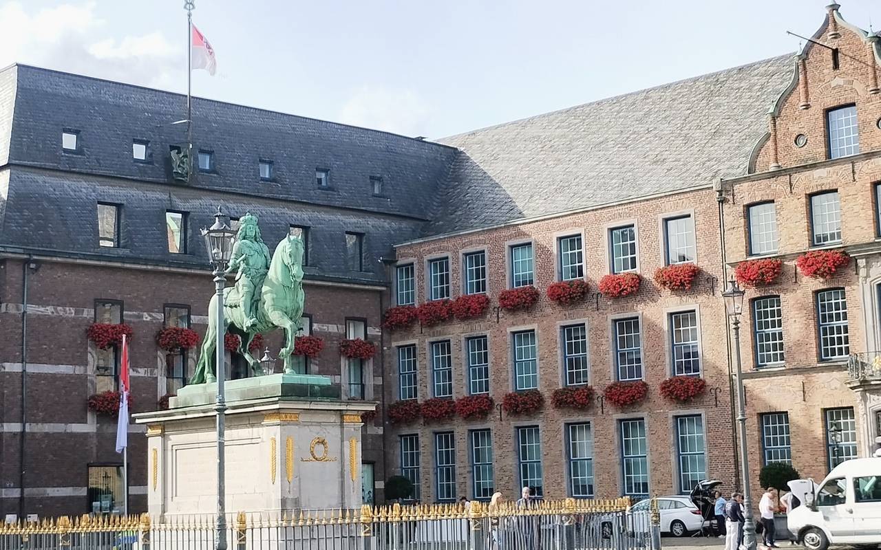 Das Düsseldorfer Rathaus mit bepflanzten Geranienkästen in der Altstadt. Davor steht die Statue von Jan Wellem.