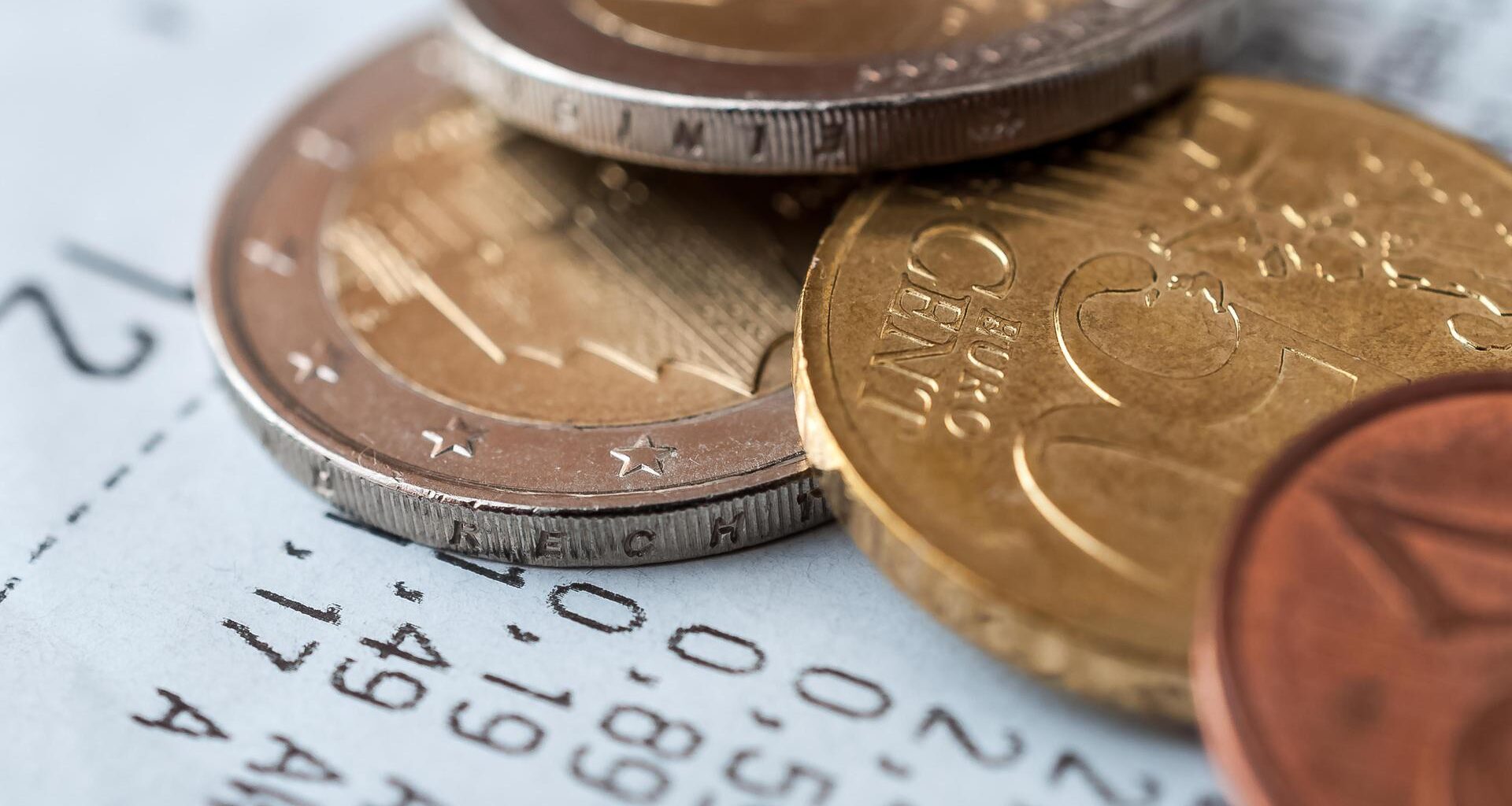 Auf einem Kassenzettel liegen verschiedene Euro-Münzen.