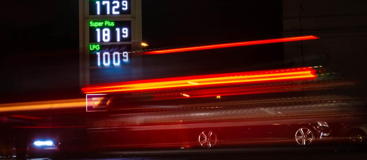 Autos fahren im Dunkeln an einer Tankstelle vorbei, die Kraftstoffpreise anzeigt (Archiv)
