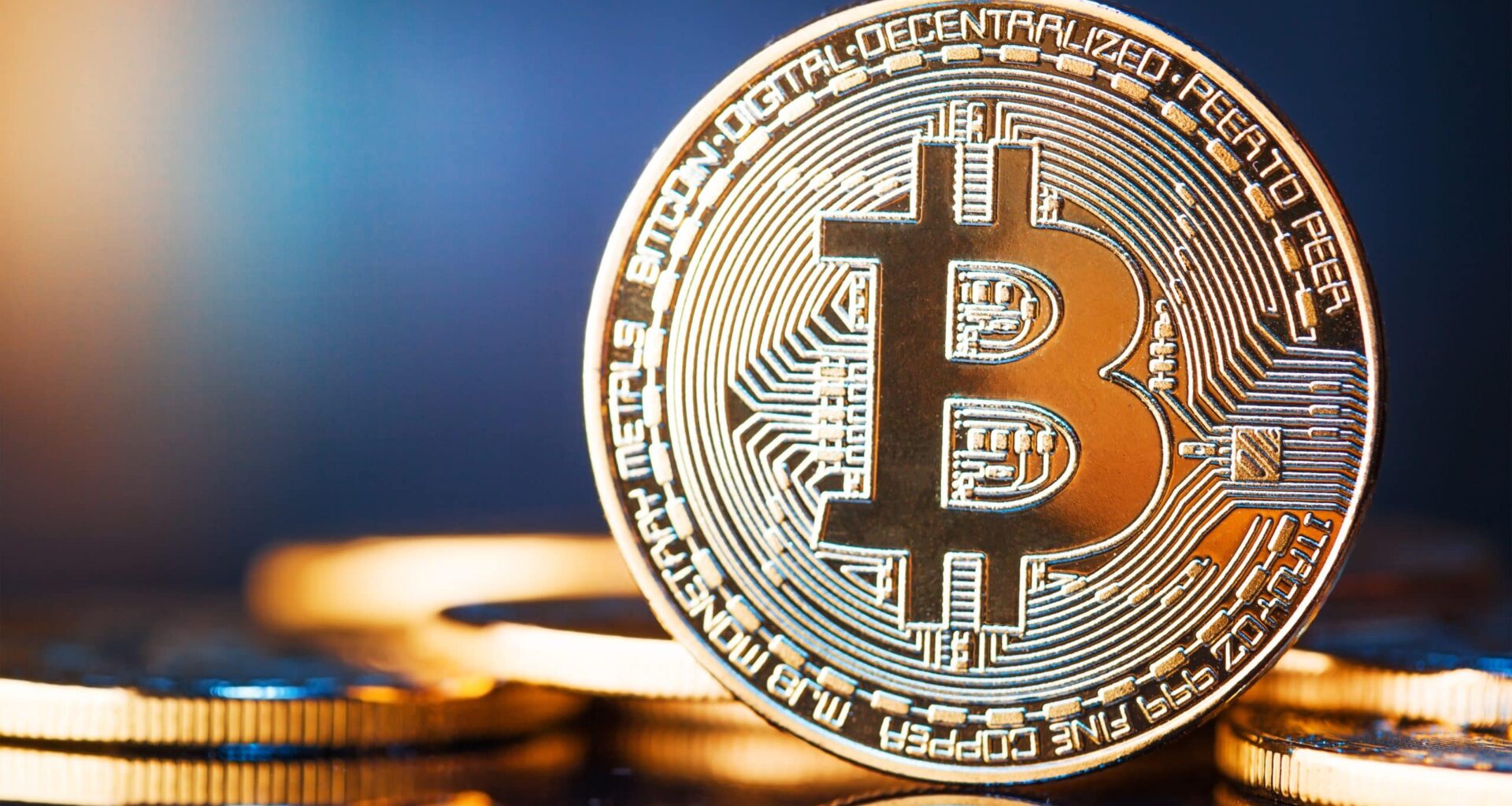 Nahaufnahme einer aufrecht stehenden physischen Bitcoin-Münze mit kreisförmigem Design, andere Münzen im Hintergrund, auf einer spiegelnden Oberfläche, die die besonderen Merkmale von Bitcoin hervorhebt.