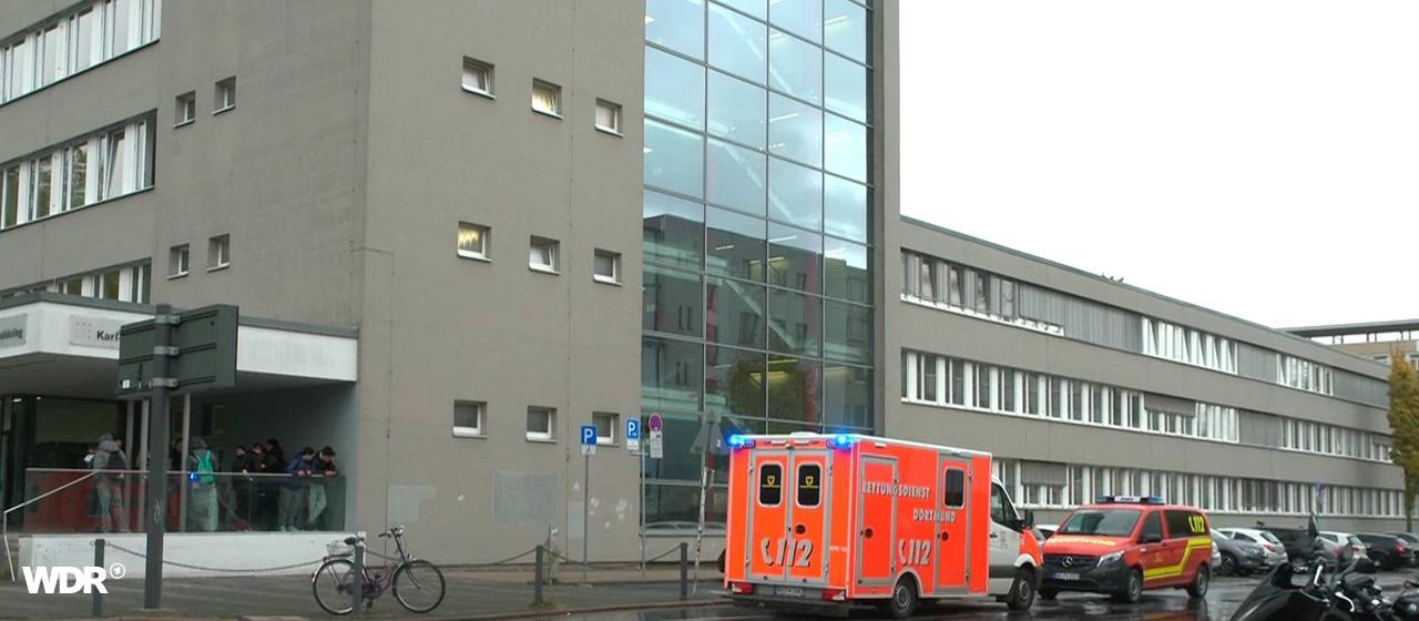 Schüsse an Karl-Schiller-Berufskolleg in Dortmund | Wickern/News 4 Video-Line TV Vor dem Karl-Schiller-Berufskolleg in Dortmund stehen Rettungswagen auf einer Straße.
