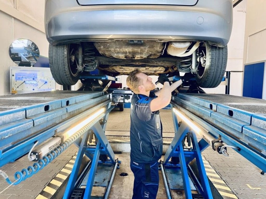 Tobias Otto untersucht beim TÜV Nord die Unterseite eines Pkw.