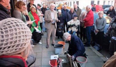 Eine Gruppe Menschen steht um eine kniende Person herum.