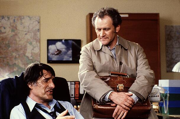 Der Monaco Franze (Helmut Fischer) mit Karl Obermayr in seiner Rolle als Spezl Manni Kopfeck. In einer Folge treibt der Monaco einen Beamten fast in den Wahnsinn, weil er seine Pension unbedingt in bar ausgezahlt haben will. Das geht jetzt bei der Deutschen Bank nicht mehr.