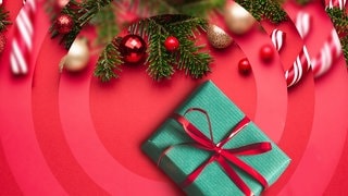 Tannenzweige, ein grün verpacktes Geschenk und rote Christbaumkugeln. (Foto: Adobe Stock Flaffy und Oleksandr Kotenko) Tannenzweige, ein grün verpacktes Geschenk und rote Christbaumkugeln.