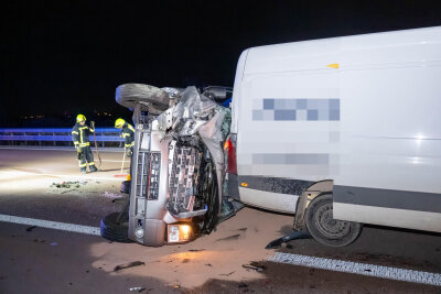Schwerer Verkehrsunfall auf der A9: Elf Menschen bei Auffahrunfall verletzt - Der Kleinbus wurde bei dem heftigen Aufprall auf die Seite geschleudert und stark deformiert – die Feuerwehr sichert die Unfallstelle und beseitigt Trümmerteile von der Fahrbahn.