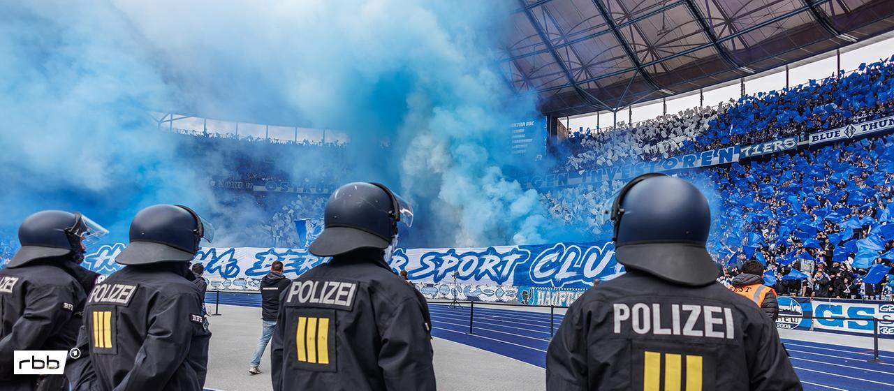Fußball: 2. Bundesliga, Hertha BSC - Dynamo Dresden, 11. Spieltag, Olympiastadion. Fans von Hertha BSC zünden Pyrotechnik mit blauem Rauch. Polizisten in Schutzkleidung sichern den Innenbereich des Stadions vor der Ostkurve. (Quelle: dpa/Andreas Gora)