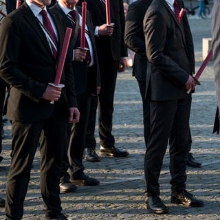 Die Mitglieder verschiedener Burschenschaften halten Fackeln in den Händen. 