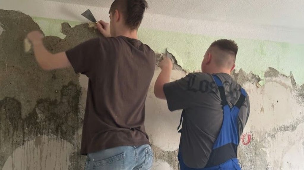 Trotz Pause arbeiten einige Neuntklässler weiter: In einer der Übungswohnungen spachteln sie alte Tapete ab.