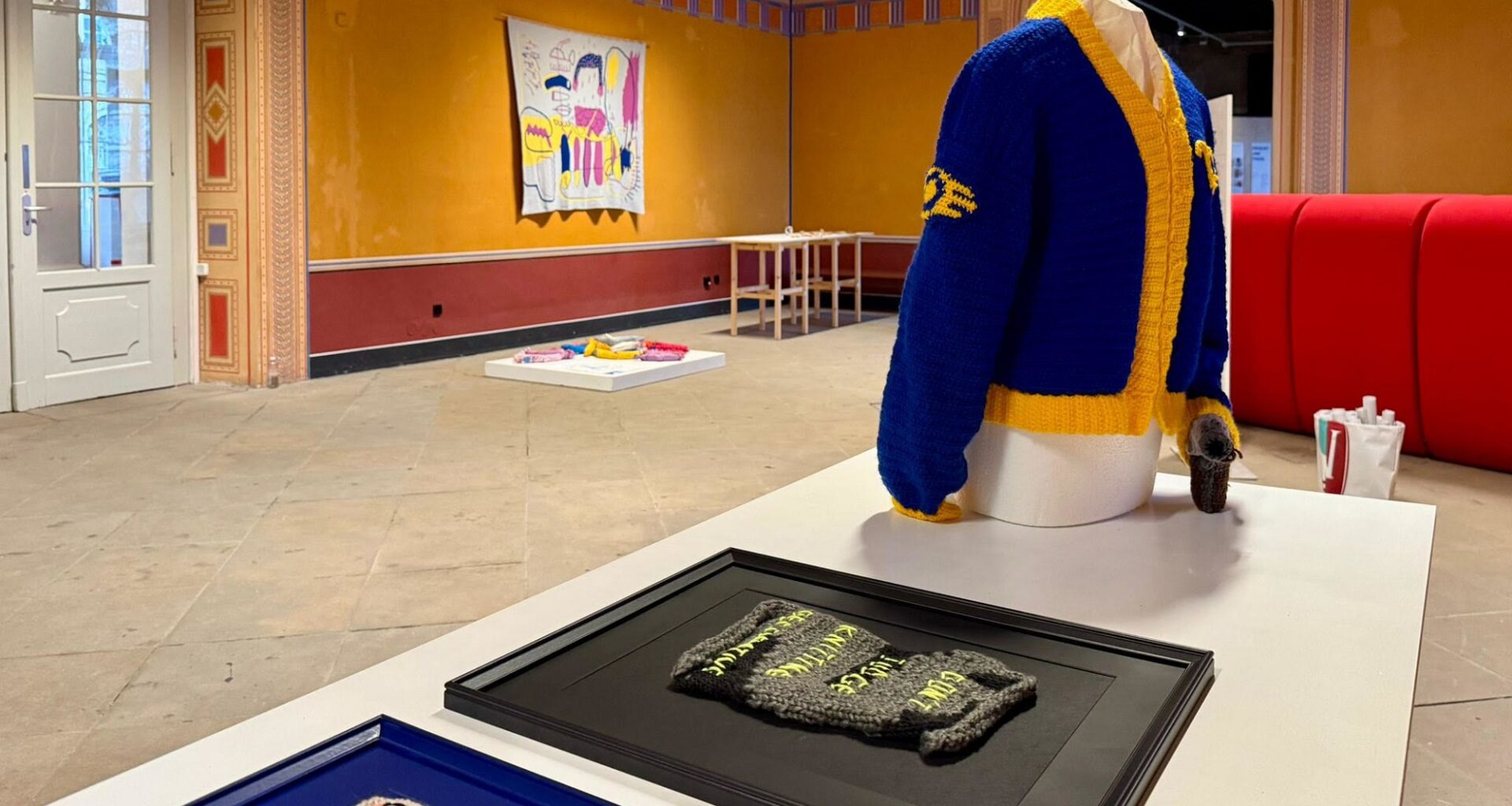 Die Wanddecke von Bettina Kletzsch im Hintergrund gab den Anstoß zur Strick-Ausstellung. Katja Gärtner und Crochet of Death zeigen mit den gerahmten Textilien und der Jacke, wie vielfältig eine Ausstellung zu dem Thema werden kann.