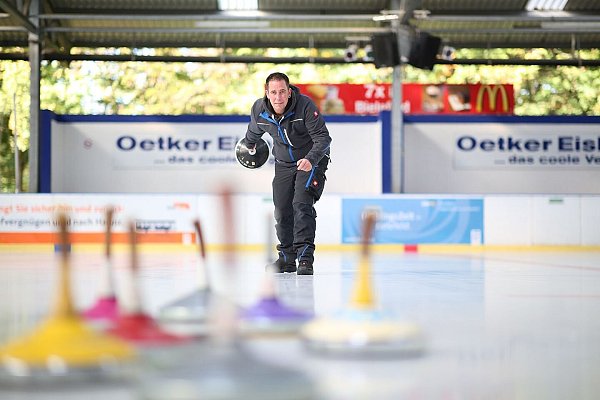Eisbahn-Leiter Louis Schröter zeigt, wie das Eisstockschießen auf der Oetker-Eisbahn in Bielefeld funktioniert. - © Oliver Krato