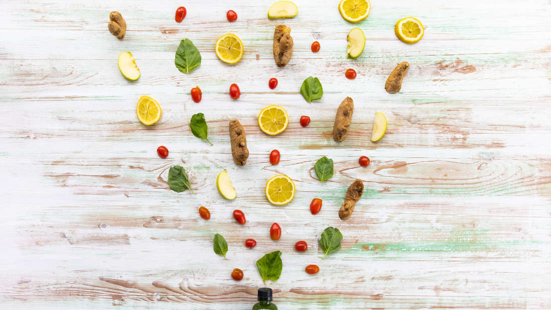 Variety ingredients of homemade mixed juice placing above a bottle of organic drinks 