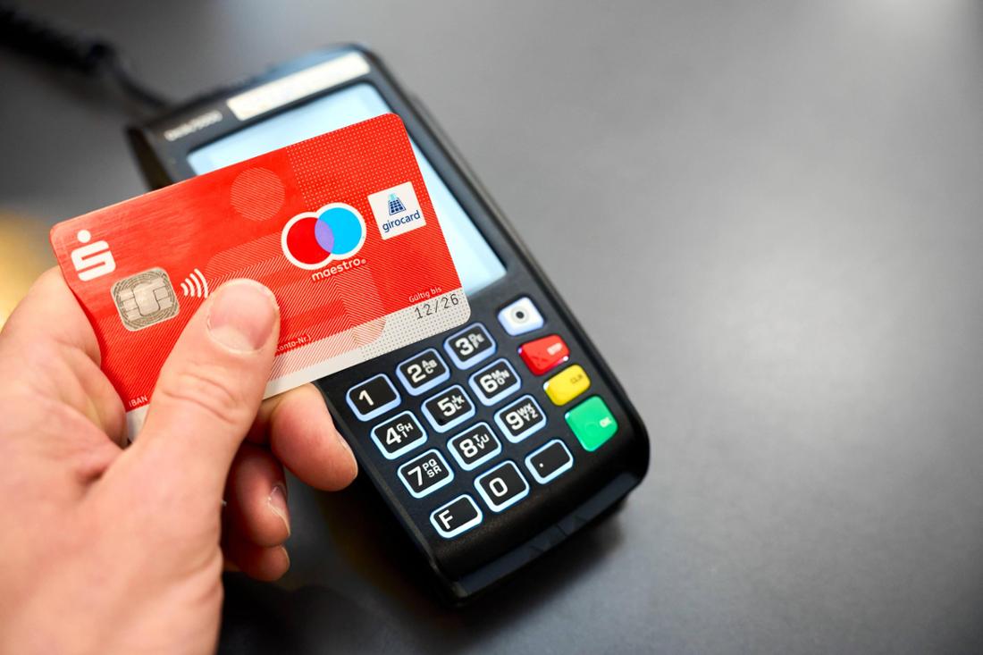 Ein Mann bezahlt kontaktlos im Supermarkt mit seiner EC-Karte. 
