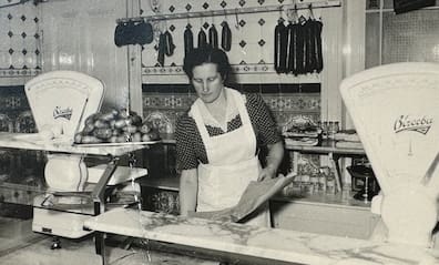 Frau Nolzen hinter der Theke der allerersten Filiale der Fleischerei Nolzen in der Gertenbachstraße, die 1935 eröffnete.