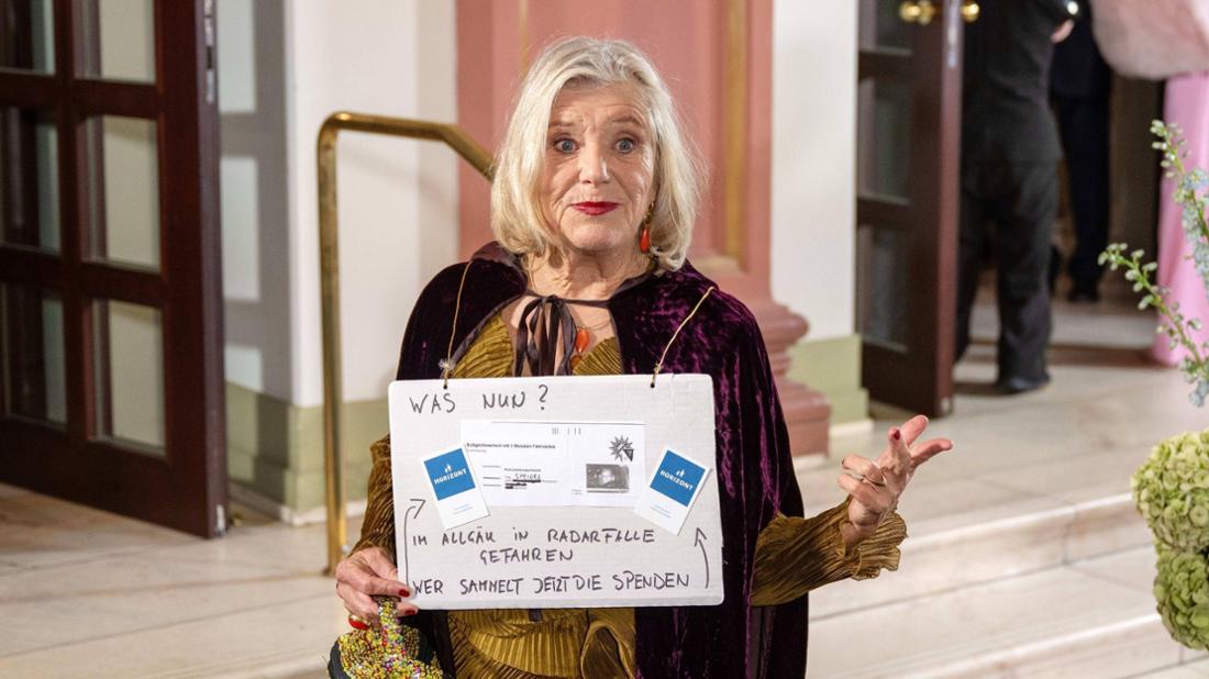Jutta Speidel beim Sportpresseball mit einem Spendenaufruf – auf dem Plakat zu sehen: unter anderem ihr Bußgeldbescheid.