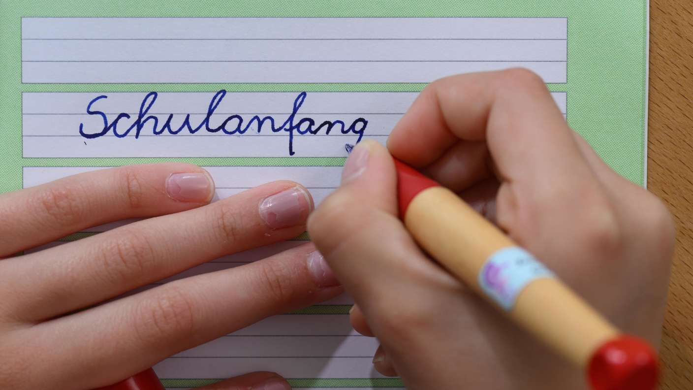 SYMBOLBILD - 06.08.2025, Sachsen, Leipzig: ILLUSTRATION - Ein Mädchen schreibt das Wort „Schulanfang“ in ein Schreibheft. (zu dpa: „Schülerzahl in Sachsen-Anhalt sinkt ab 2026“) Foto: Hendrik Schmidt/dpa +++ dpa-Bildfunk +++